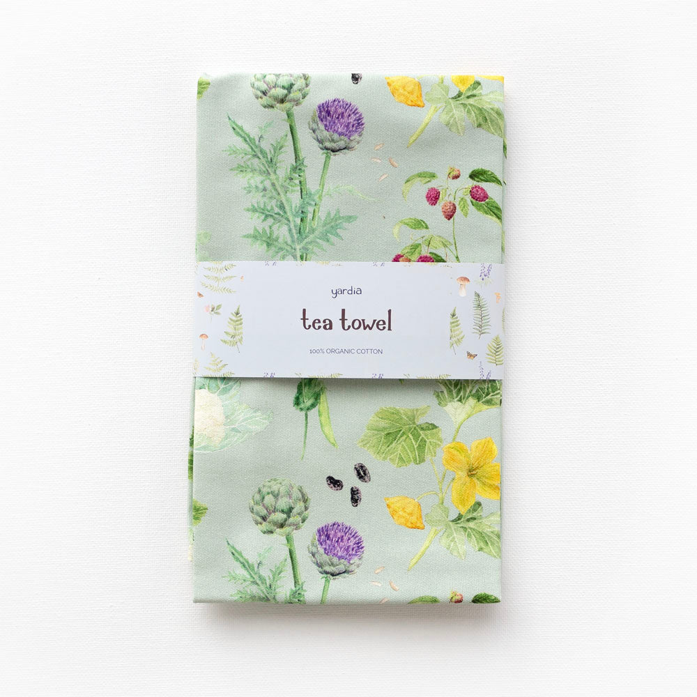 Kitchen Garden Tea Towel with a white label featuring a green and yellow floral design, crafted from 100% organic cotton for kitchen use.