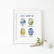 West Seattle Watercolor Art Print featuring seasonal park scenes in a white frame, alongside a candle holder with leaves. Frame not included.