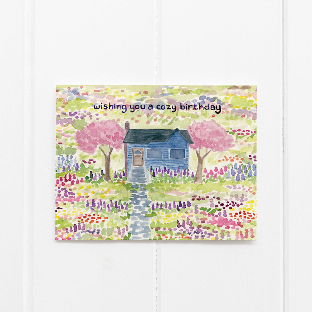 Cozy Birthday Card featuring a watercolor illustration of a cottage surrounded by wildflowers, hand-lettered by Seattle artist Brigida Swanson, blank inside with a kraft envelope.