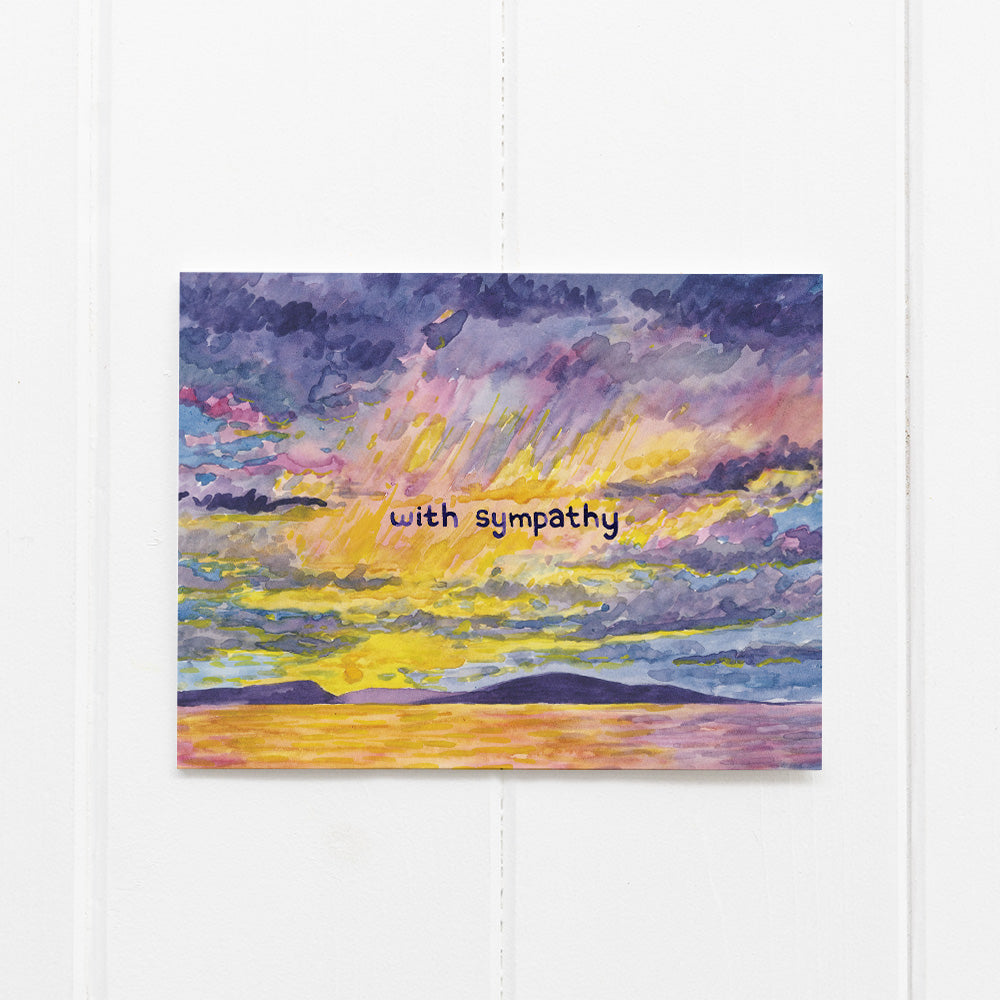 With Sympathy Card featuring a watercolor sunset illustration off Seattle's Alki Beach, blank inside, paired with a kraft envelope, designed by artist Brigida Swanson.
