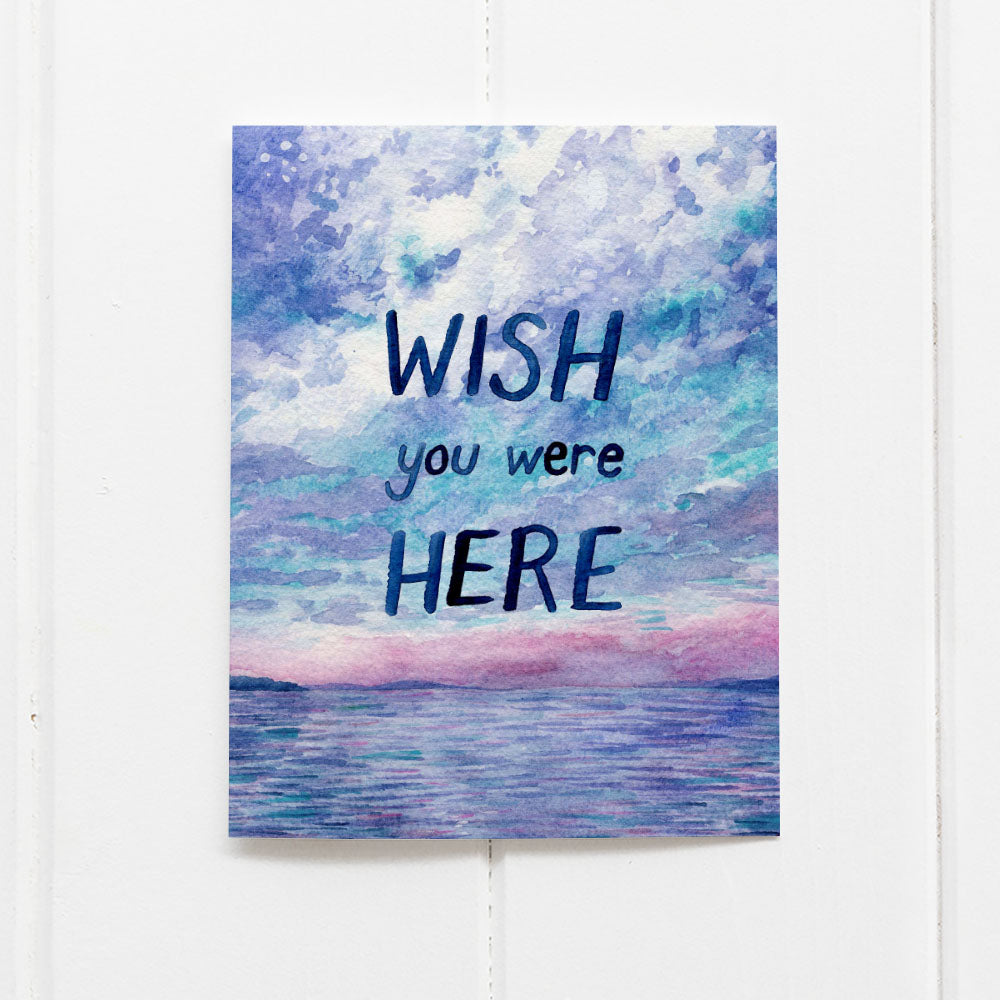 Wish You Were Here Card featuring a watercolor sunset over the Pacific Northwest coastline, hand-lettered by Seattle artist Brigida Swanson, blank inside for personal messages.