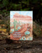 Warm Holiday Wishes Card featuring a watercolor desert landscape with cactus and pine cones, professionally printed on recycled cardstock, blank inside with kraft envelope.