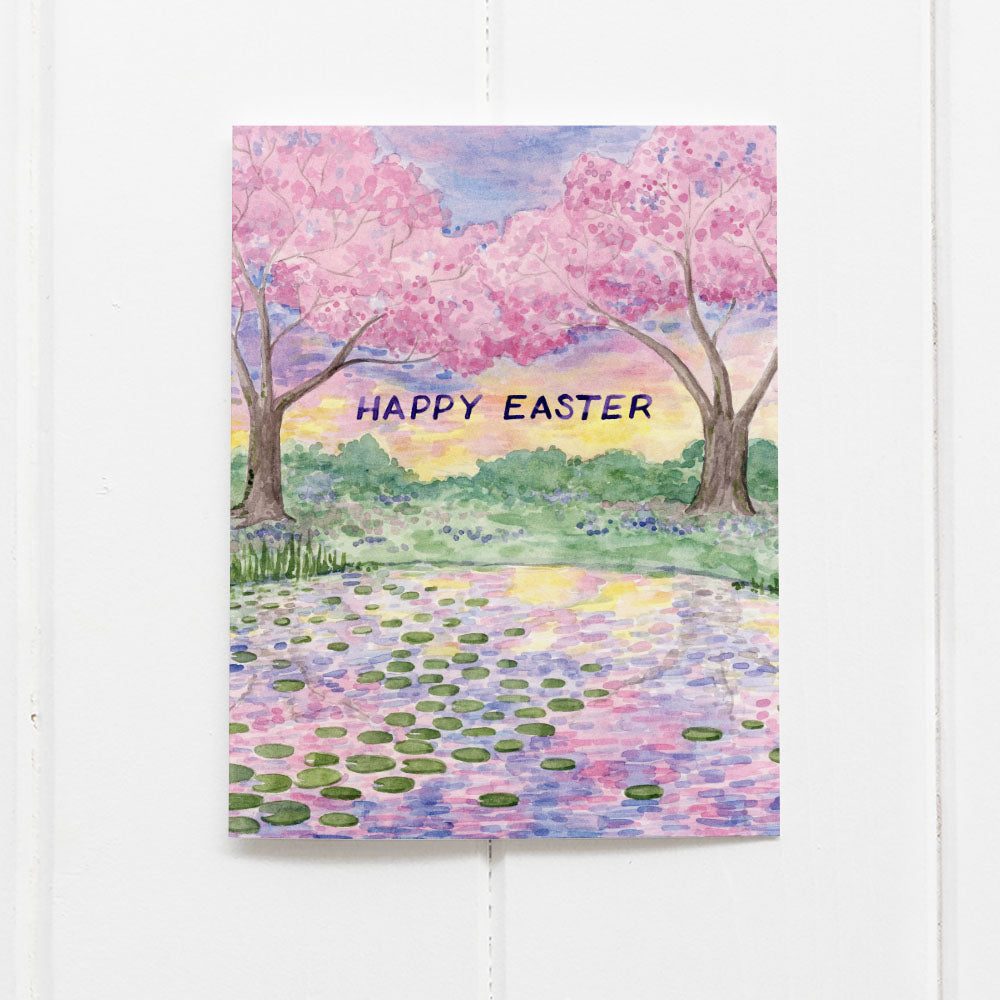 Happy Easter Card featuring a watercolor of cherry blossom trees and a lily pond, designed by Brigida Swanson, blank inside for personal messages.