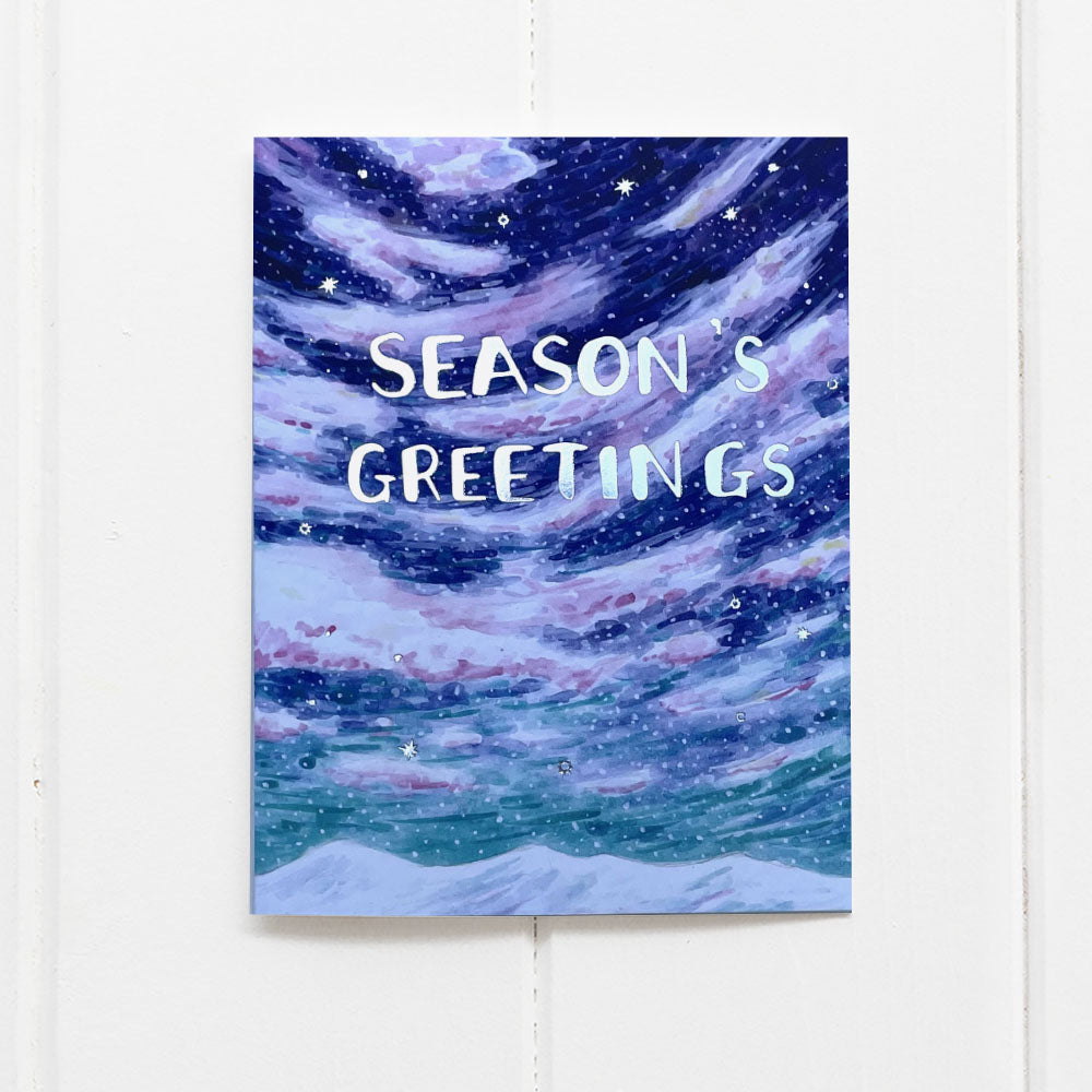 Season's Greetings Holiday Card with watercolor snowy sky scene, silver foil snowflakes, and lettering. Blank inside, includes a kraft envelope, designed by Brigida Swanson.