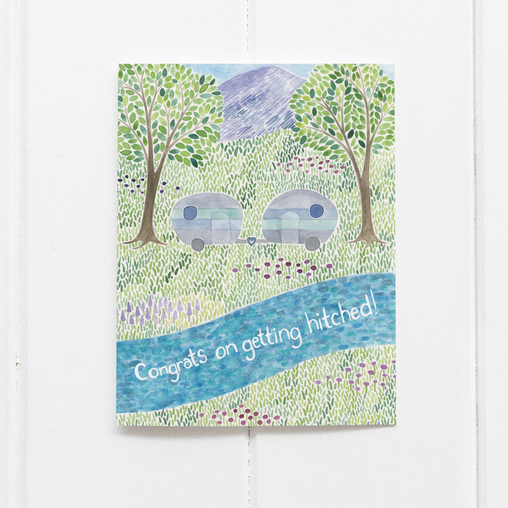 Camper Wedding Card featuring watercolor campers and trees, celebrating adventurous couples with a Congrats on getting hitched! message. Comes with a kraft envelope.