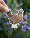 Hand holding a Speckled Sussex Hen watercolor sticker by artist Brigida Swanson, ideal for laptops or water bottles, embodying Yardia's nature-inspired artistry.