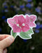 Hand holding a Bougainvillea - Watercolor Wildflower Sticker, featuring a detailed flower illustration, ideal for decorating surfaces like laptops or water bottles.