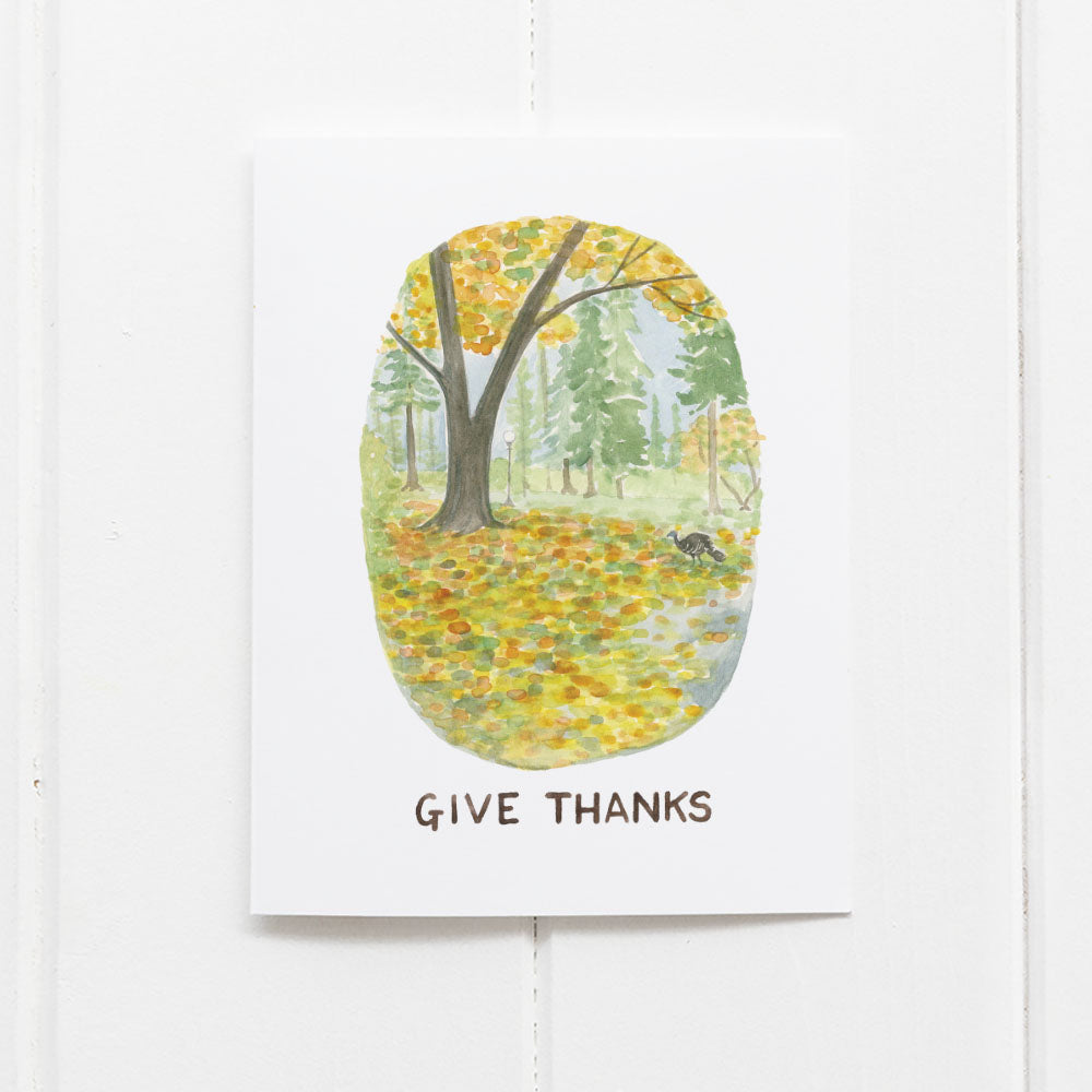 Thanksgiving Card with a watercolor illustration of an autumn park featuring a wild turkey and a give thanks message. Blank inside, includes a kraft envelope.