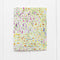 Multilingual Many Thanks Card featuring a watercolor meadow illustration and hand-lettered text in various languages, printed on recycled cardstock with a blank interior.