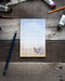 Chicken Scratch Pad Notepad featuring two watercolor chickens, Pumpkin and Agatha, with hand-lettered Scratch Pad text on a wooden surface with a blue pencil.