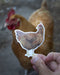 Hand holding a vinyl sticker of a Rhode Island Red chicken, featuring a watercolor illustration by Brigida Swanson, ideal for laptops or water bottles.