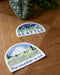 Seattle Sticker featuring a watercolor illustration of the Seattle skyline with Mt. Rainier, designed by Brigida Swanson, displayed on a table.