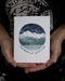 Mountains of Gratitude Thank You Card showing a hand-drawn Cascade Mountain scene under Northern Lights, held in a person's hand, blank inside for personal messages.