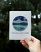 Hand holding the Wonders Ahead Congratulations Card featuring a watercolor illustration of a girl hiking, designed for nature lovers.