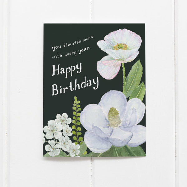 You Flourish More With Every Year - Floral Birthday Card featuring watercolor magnolia and poppy illustrations, blank inside, folded, with a heartfelt message on the front.