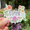 Person holding the Lesbian Voter Sticker, a durable vinyl sticker featuring a watercolor floral design, symbolizing LGBTQ+ pride and voter identity.