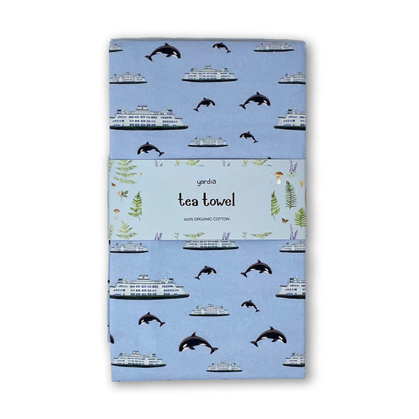 Ferry Tea Towel - Organic Cotton Kitchen Towel featuring a watercolor pattern of ferries and orcas, wrapped in a label, emphasizing Pacific Northwest charm and sustainability.