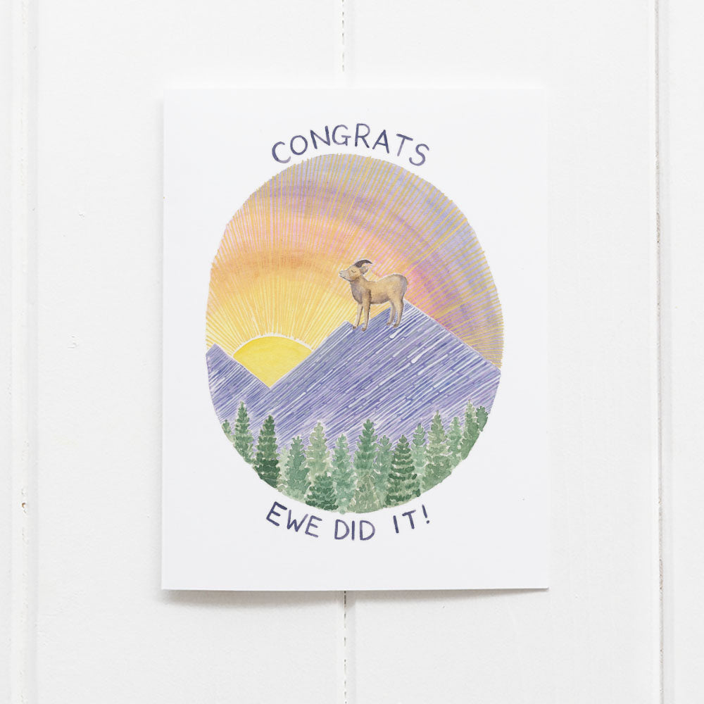 Congratulations card with watercolor illustration of Rocky Mountain sheep on top of a mountain peak, and text reading Congrats ewe did it