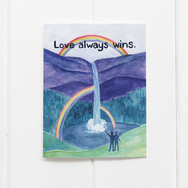 Love Wins Card by Yardia with watercolor illustration of two men observing rainbows at a waterfall and text reading Love Always Wins