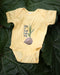 grow at your own pace baby one piece in butter yellow, pictured on rhubarb leaf