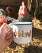 Hand holding an enamel mug featuring watercolor chickens, highlighting its rustic charm and connection to nature, ideal for cozy winter beverages.